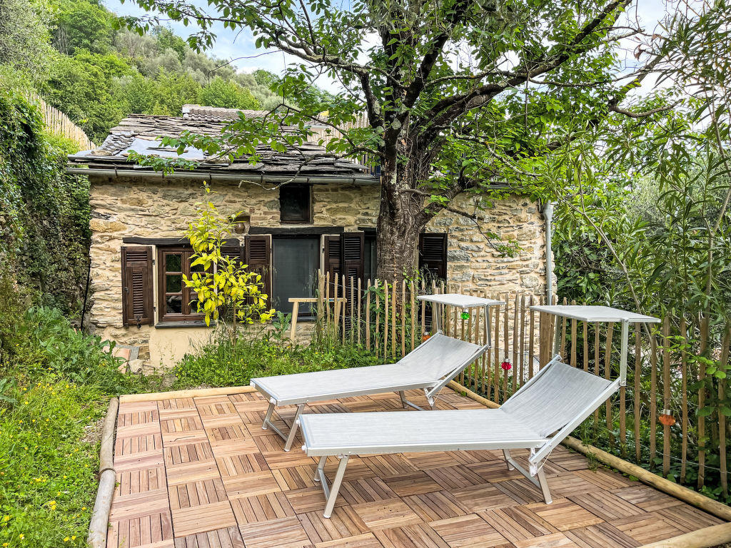Grosszügige Terrasse mit Liegestühlen und Blick auf das Steinhaus